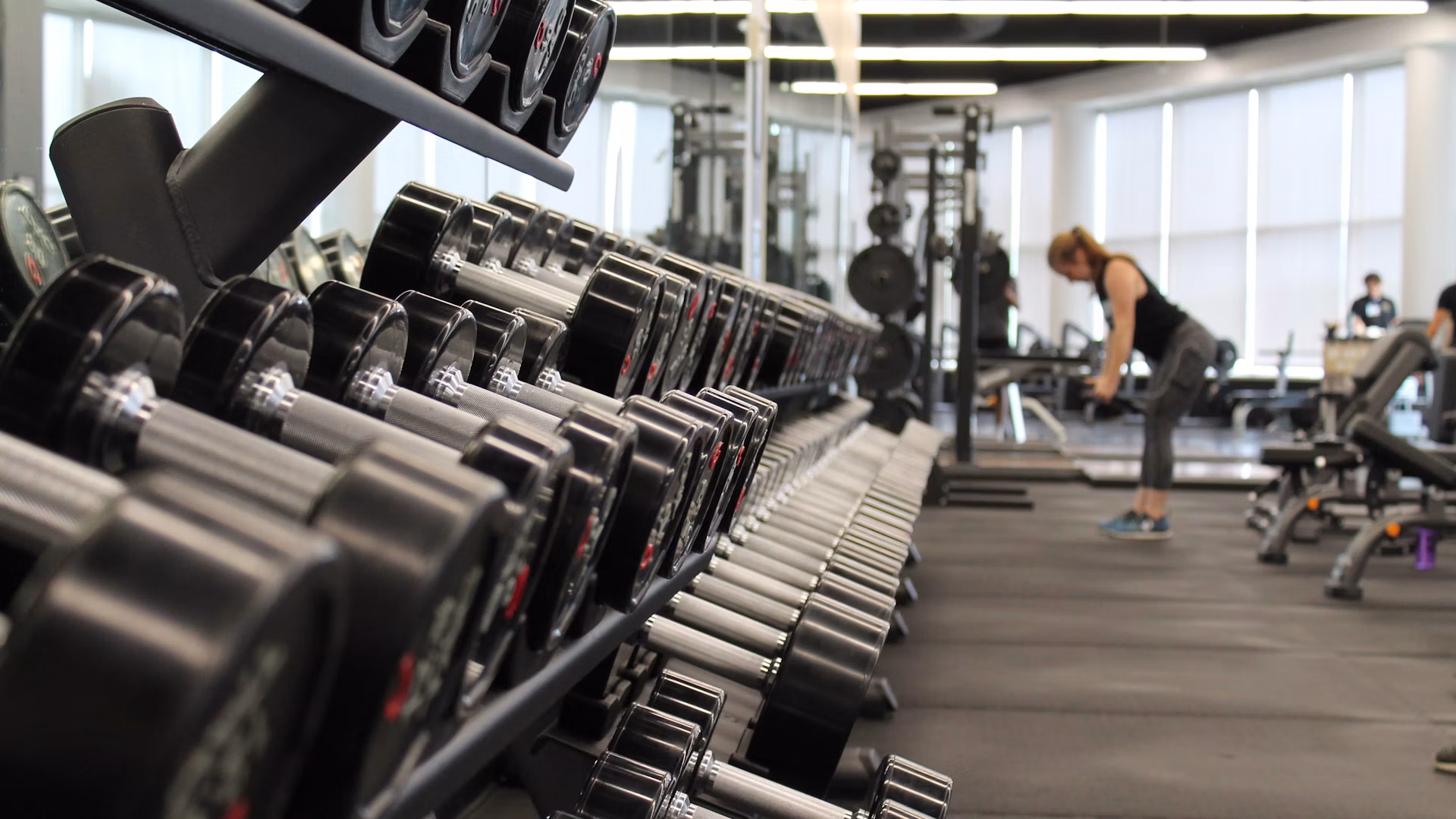 A dimly lit weights floor, racks loaded and chalk dust in the air